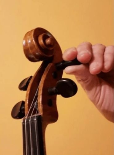 afinar el violin utilizando las clavijas para tensar o destensar la cuerda