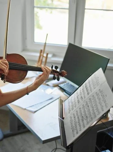 persona practicando violin con una partitura y un tutorial